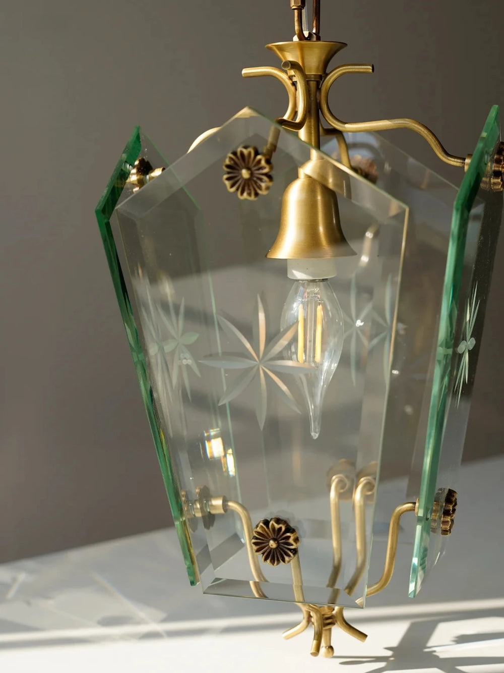 Decorative hanging lamp with glass shade and brass fixtures on a neutral background