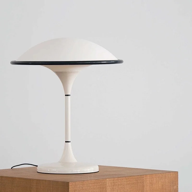 White table lamp with a black rim on a wooden surface against a light gray background