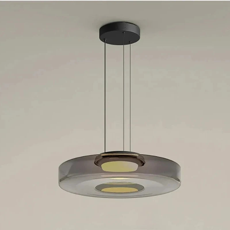 Smoke grey glass disk pendant light with a black ceiling mount and cord.