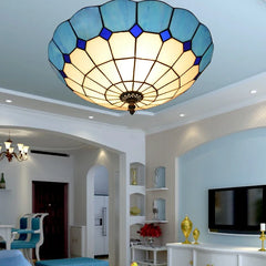 A blue stained glass ceiling light with a scalloped edge installed in a living room above a TV.