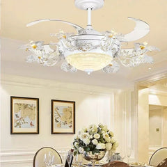 A white ceiling fan light with decorative floral elements and clear crystal accents, installed in a dining room setting.