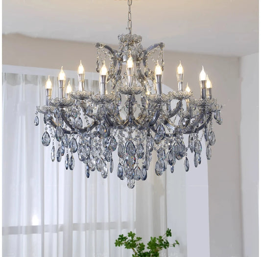 A large, ornate crystal chandelier with a grey metal frame and numerous teardrop crystals hanging from candle-style light fixtures.