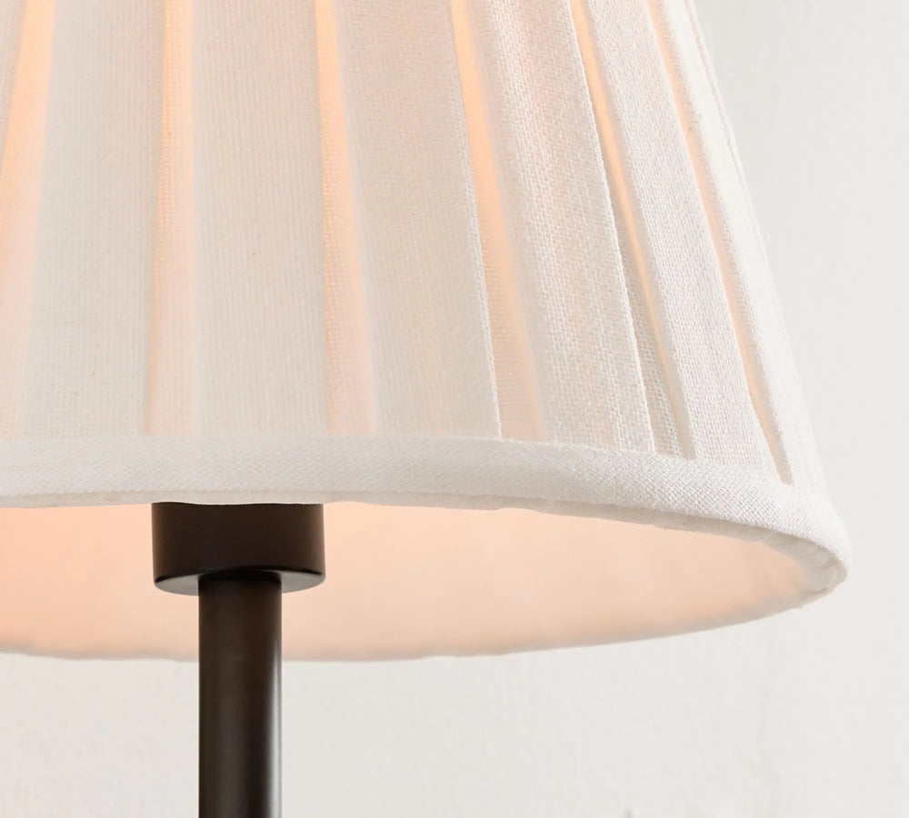 Close-up of a lamp with a white shade and black base on a light gray background