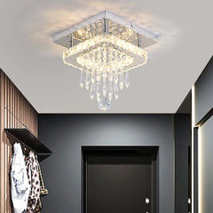 A chrome and crystal tiered ring flush mount ceiling light installed in a modern hallway with wood paneling.