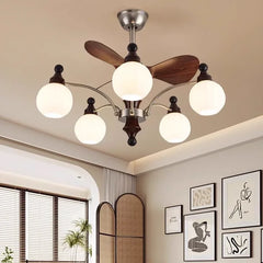 A metallic silver sputnik starburst ceiling fan chandelier with wooden blades and frosted glass globe lights, set against a neutral wall with artwork.