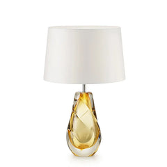 Yellow glass swirl table lamp with a cream fabric shade on a white background