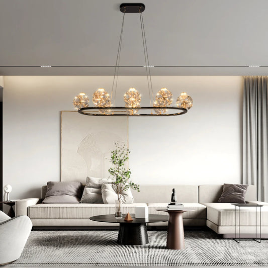 Gold linear pendant light with crystal orb lights over a sectional sofa.