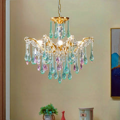 A gold cascading chandelier with pink and green teardrop crystals displayed above a piece of furniture.