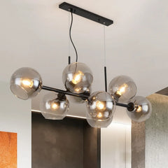 An interior shot of a living room featuring a black linear chandelier with transparent glass globes and visible Edison-style bulbs.