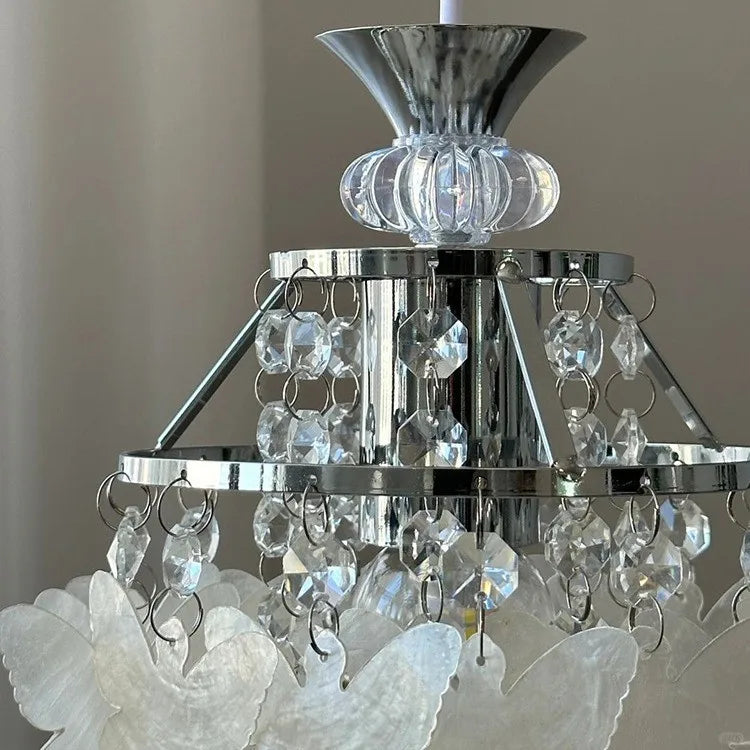 Detailed view of the top section of a chrome pendant light, showing crystal strands and faceted accents.