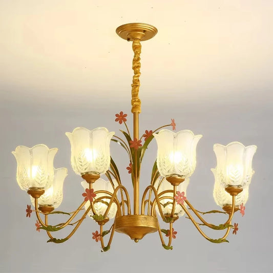 Gold chandelier with floral accents and frosted glass shades, hanging from a ceiling.