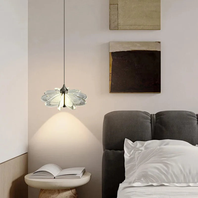 Modern bedroom with a pendant light, bed, and open book on a side table.
