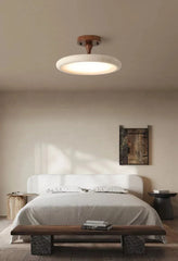 A bedroom with a contemporary aesthetic, centered around a stone and wood ceiling light fixture, with minimalist decor and natural light.