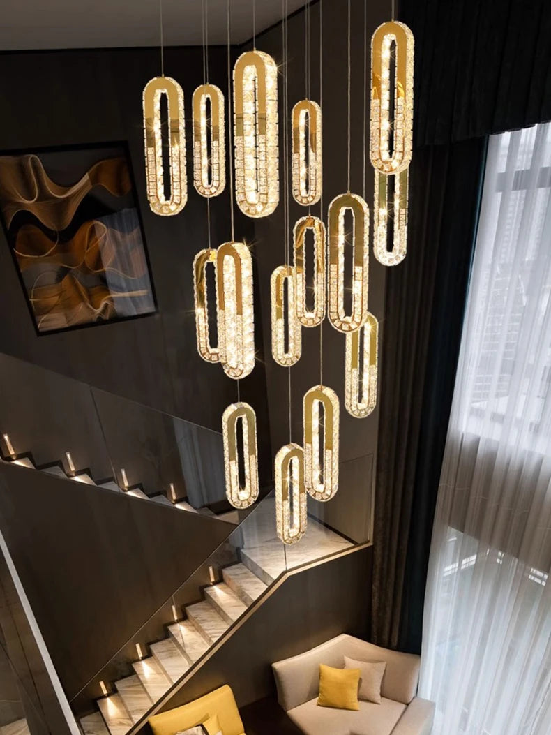 Modern chandelier hanging in a stylish interior setting with staircase and sofa.