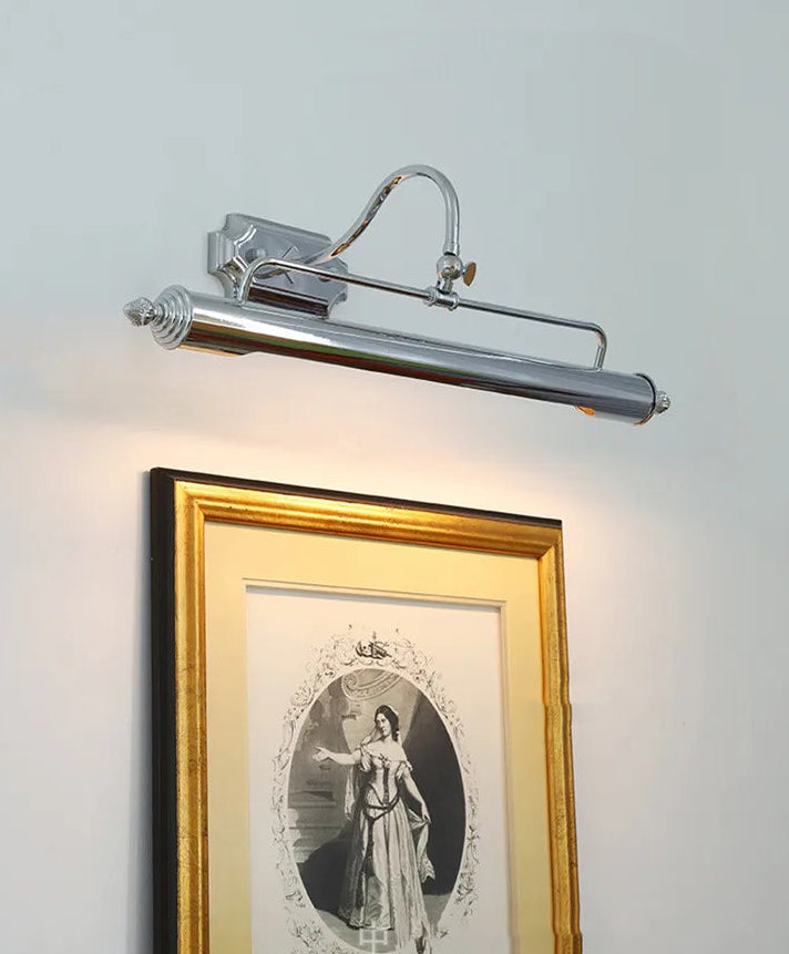 Wall-mounted light fixture illuminating a framed picture on a wall.