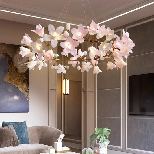 Close-up of a circular chandelier with intricate pink flower lights and gold branches, glowing softly.