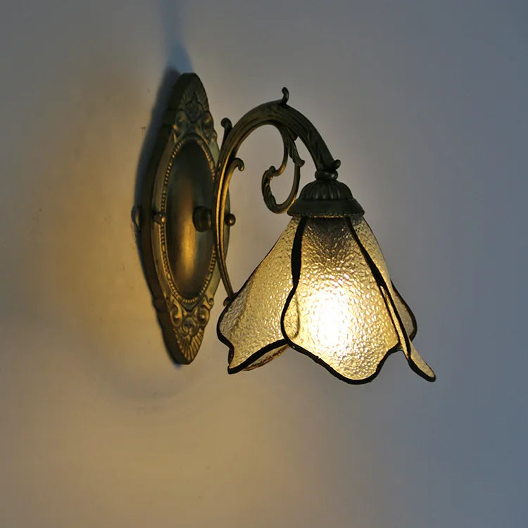 Decorative wall sconce with glass shade on a plain wall