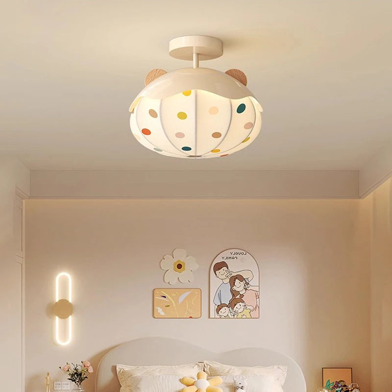 White ceiling light shaped like a hot air balloon with colorful polka dots and wooden bear ears, mounted on a white ceiling.