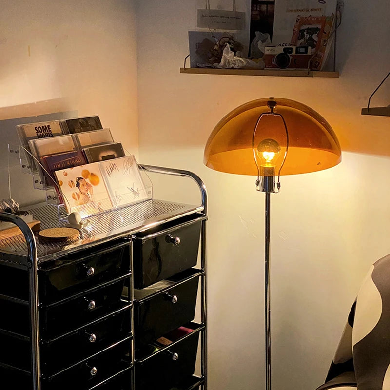 An amber mushroom-shaped floor lamp illuminates a corner with shelves displaying items.