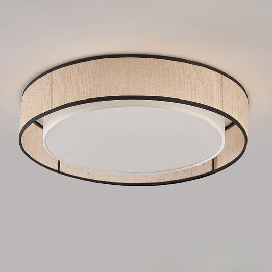 Ceiling view of a round flush mount light with a beige fabric shade and black trim, showing a white acrylic diffuser in the center.