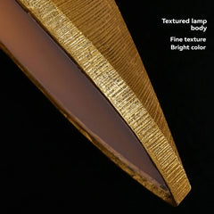 Side view of a golden linear pendant light showing its elongated shape and suspension