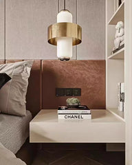 Close-up of a bedside table with a small plant and books, featuring a pendant light hanging above.