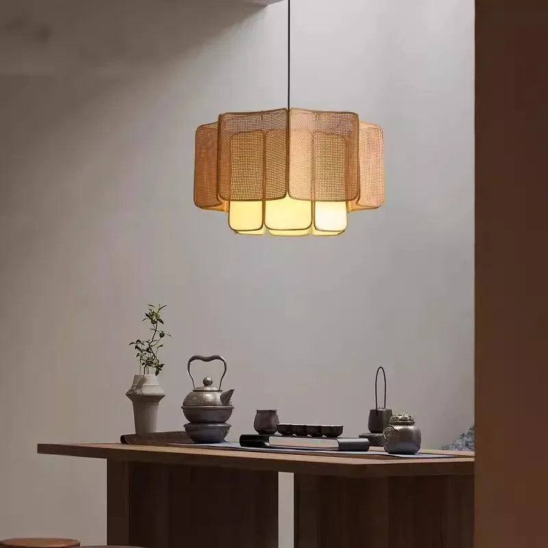 A natural-toned rattan woven tiered pendant light hanging above a wooden table in a room with soft ambient lighting.