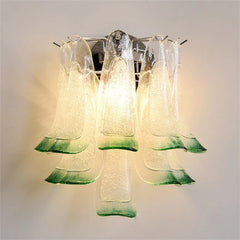 Green and clear glass petal wall sconce with a chrome finish, mounted on a white wall.