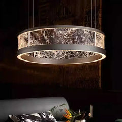 A large, dark-finished ring pendant light with a textured glass diffuser, hanging above a sofa and coffee table in a dimly lit room.