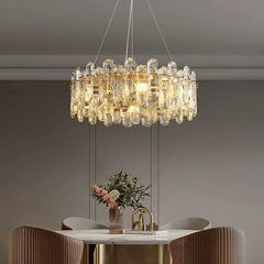 Close-up view of a gold chandelier featuring clear crystals and internal LED lights, positioned above a dining table.