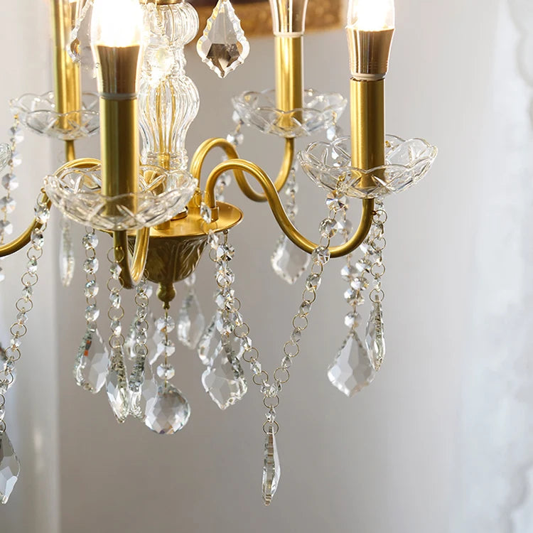 Close-up of a gold chandelier with crystal elements against a neutral background