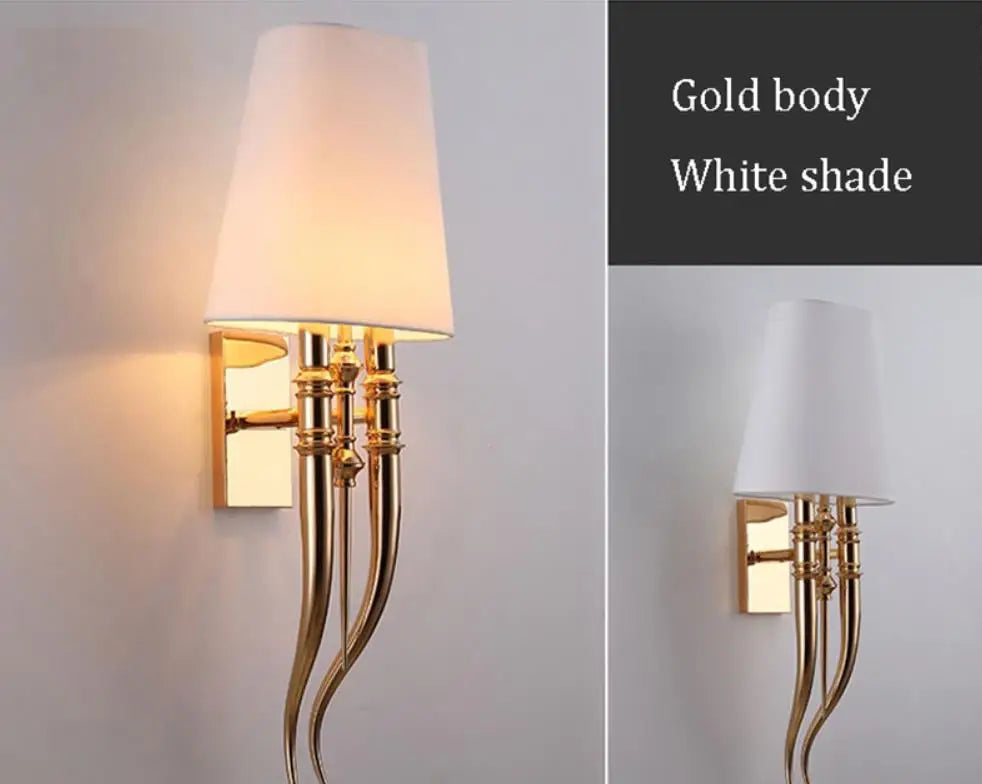 Wall sconce with gold body and white shade on a gray background