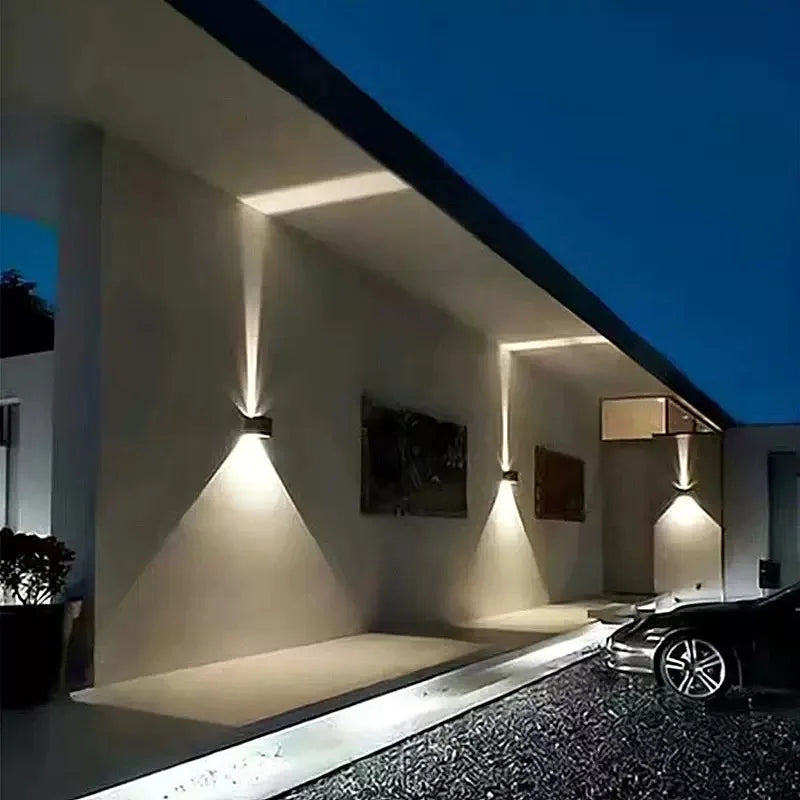 Modern house exterior with wall-mounted lights and a car parked outside.
