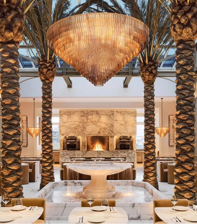 Luxurious interior with palm trees, chandelier, and stone fireplace.