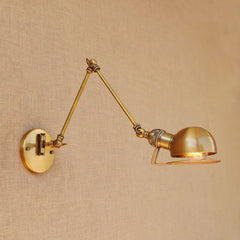 A brass swing arm wall sconce with a dome-shaped metal shade, mounted on a textured wall.