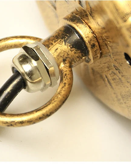Close-up of a brass light bulb socket with black wiring on a white background