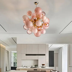 Gold glass ball cluster pendant light with frosted and clear orbs installed in a modern living room with white cabinetry.