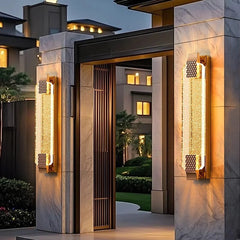 Two black wall sconces with clear crystal diffusers flanking a dark modern door.