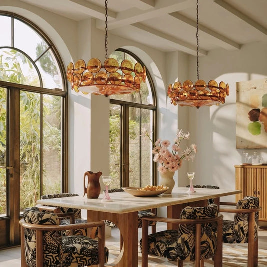 Two amber glass disc chandeliers hanging over a dining table.