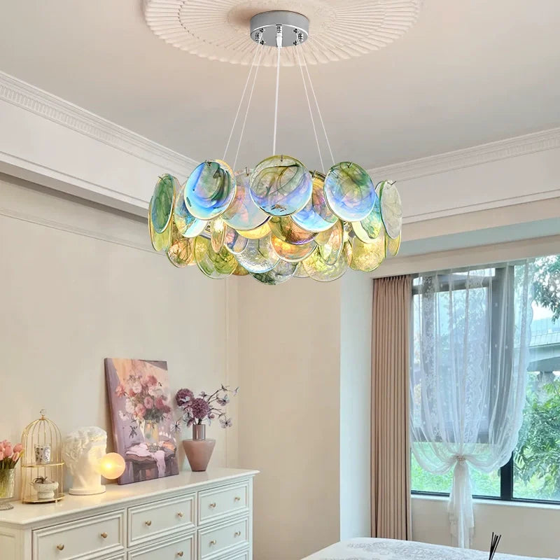 A colorful Murano-style glass disc chandelier with a polished metal frame, suspended from a white ceiling with decorative molding.