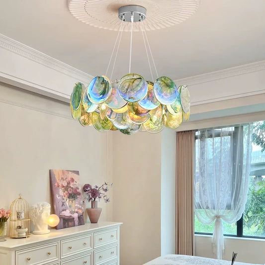 A colorful Murano-style glass disc chandelier with a polished metal frame, suspended from a white ceiling with decorative molding.
