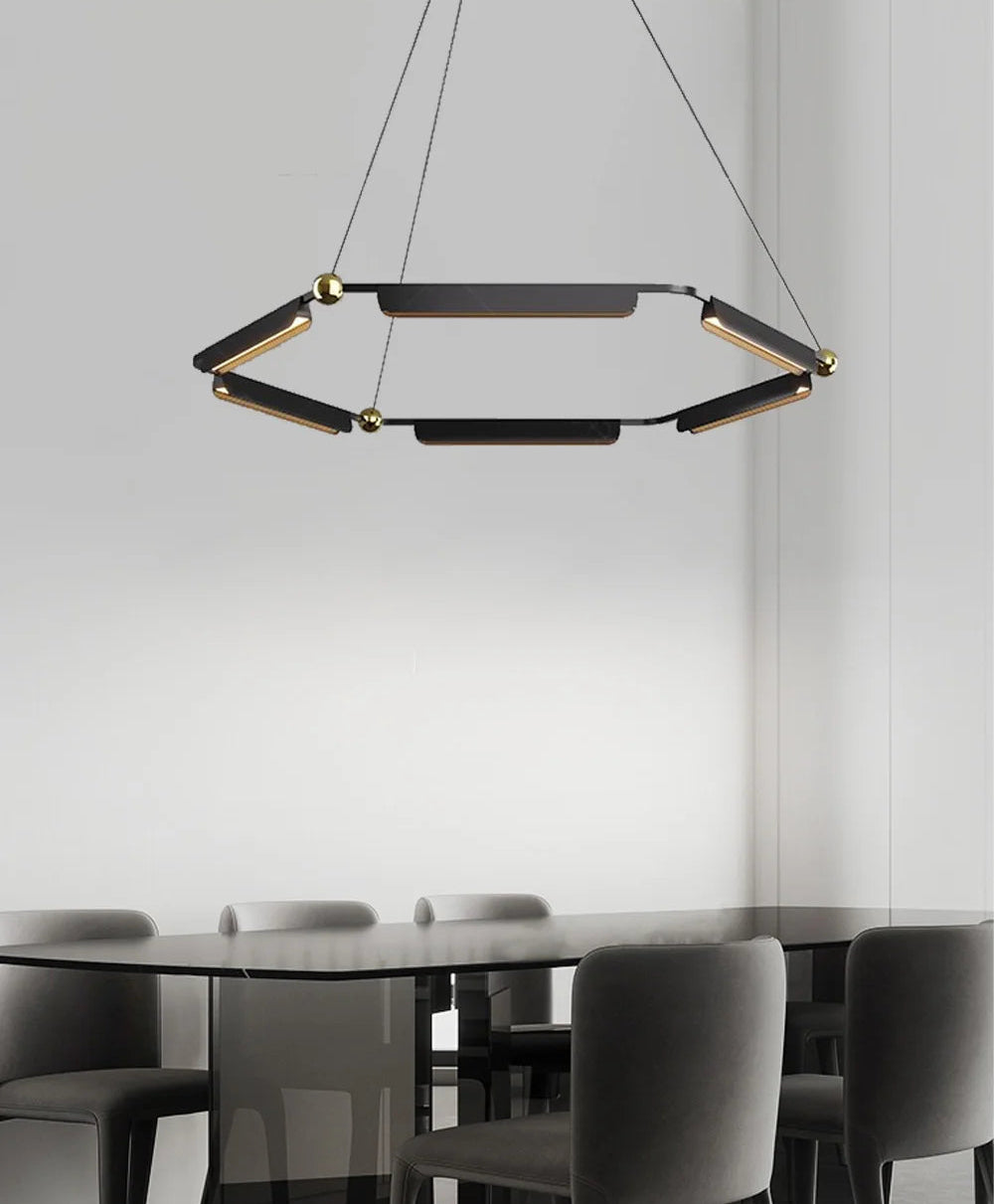 Modern black pendant light hanging above a dining table with chairs in a minimalistic setting.
