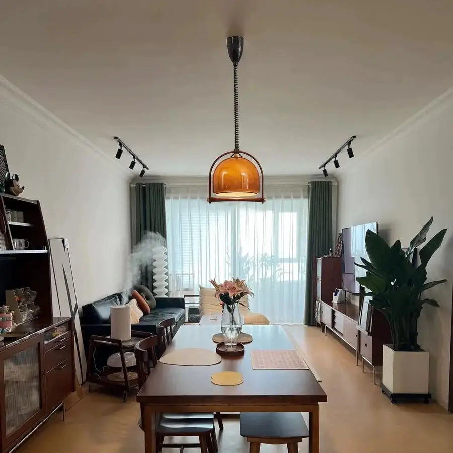 Dining room setting with an amber glass dome pendant light centered above the table.