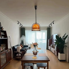 Dining room setting with an amber glass dome pendant light centered above the table.
