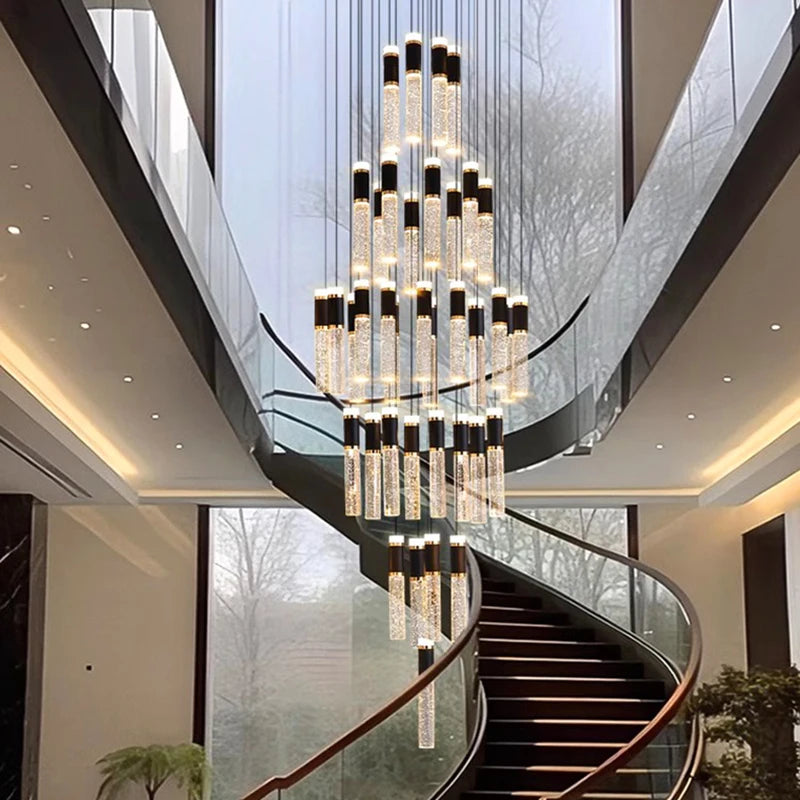 Luxurious chandelier hanging in a modern staircase with glass walls and wooden steps.