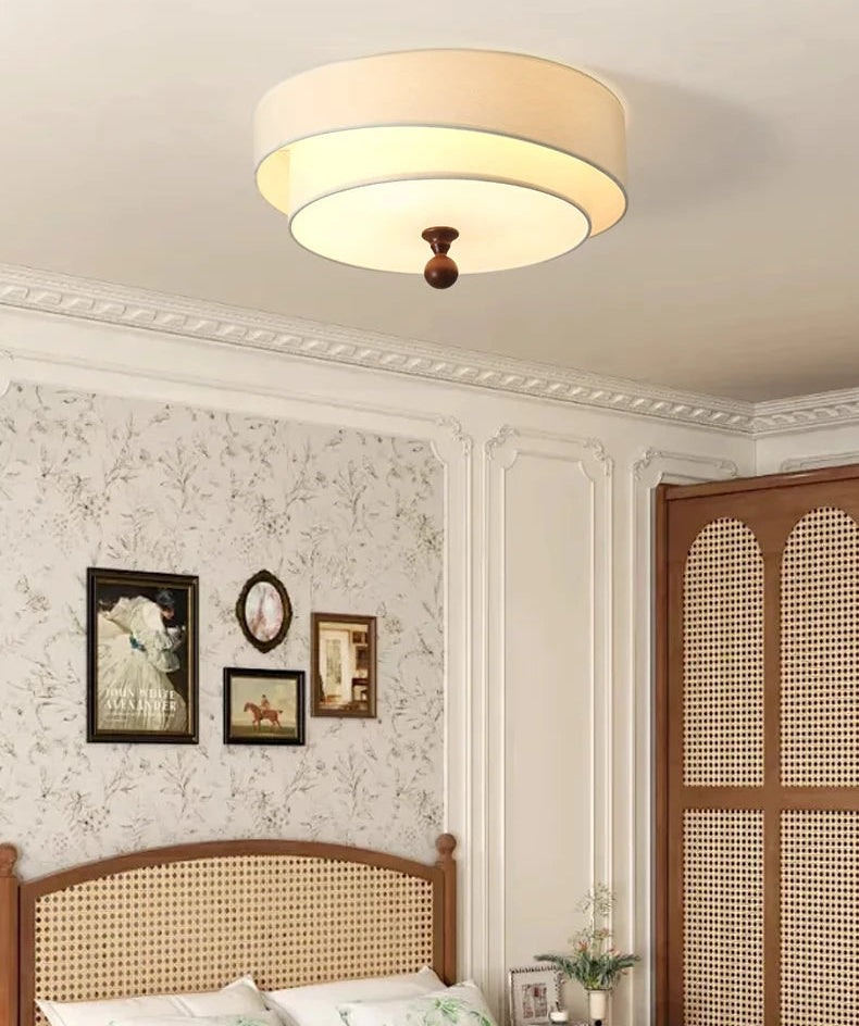 Ceiling light fixture in a bedroom with floral wallpaper and wooden headboard.