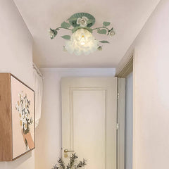 A single green floral flush mount ceiling light mounted on a ceiling in a hallway with a white door and artwork on the wall.