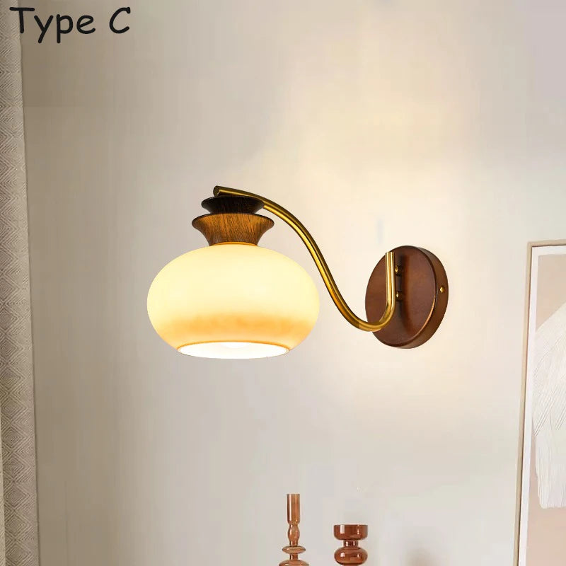 Wall sconce featuring a wooden mount, a curved brass arm, and a globe-shaped frosted glass shade.