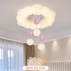 White cloud-shaped ceiling light with pink butterflies and hanging orbs, viewed from a slightly lower angle in a bedroom.