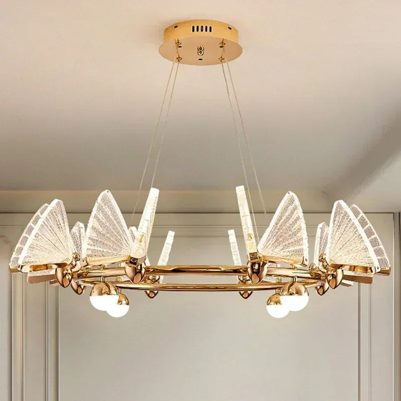 Gold chandelier with clear, translucent butterfly-shaped shades and globe lights, mounted on a ceiling.